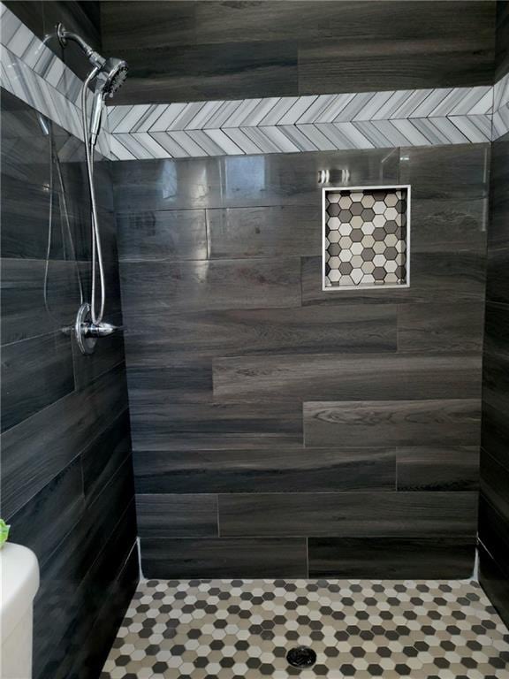 bathroom featuring tiled shower and toilet