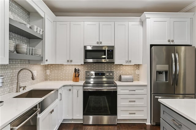 kitchen with appliances with stainless steel finishes, light countertops, a sink, and open shelves