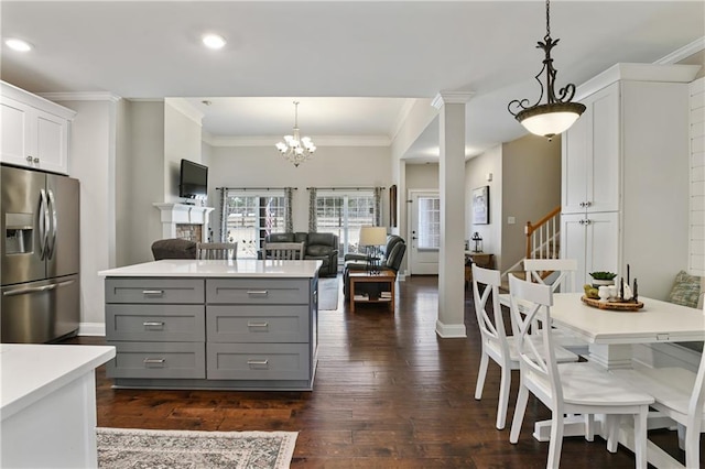 kitchen with dark wood-style flooring, hanging light fixtures, gray cabinets, light countertops, and stainless steel refrigerator with ice dispenser