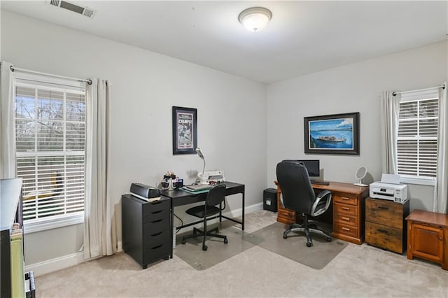 office space with baseboards, plenty of natural light, visible vents, and light colored carpet