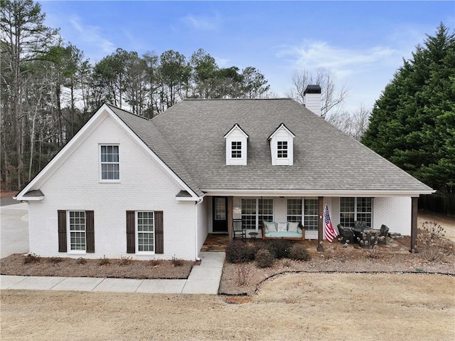 view of front of home featuring brick siding, a chimney, and a shingled roof