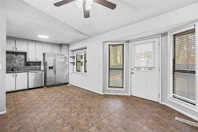 kitchen featuring lofted ceiling, sink, ceiling fan, stainless steel appliances, and decorative backsplash