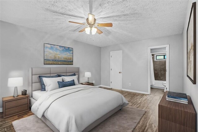 bedroom with ceiling fan, light hardwood / wood-style floors, a textured ceiling, and ensuite bathroom