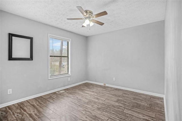 empty room with a textured ceiling, wood-type flooring, and ceiling fan