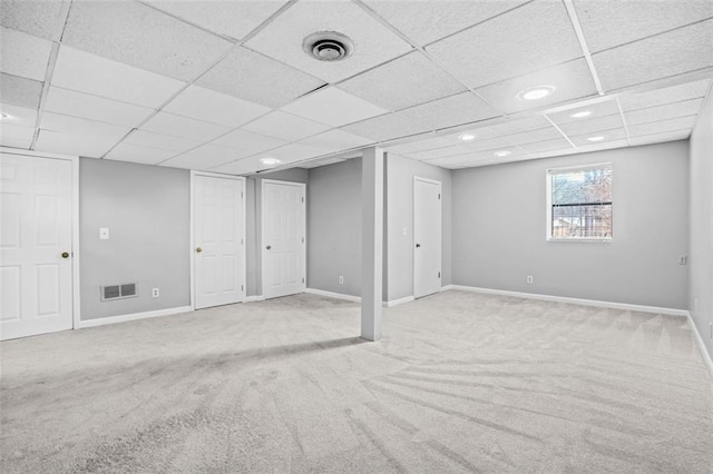 basement with a paneled ceiling and light colored carpet