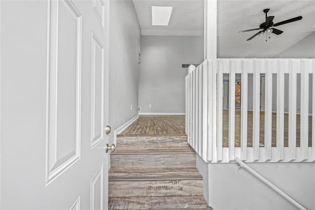 staircase with ceiling fan, lofted ceiling with skylight, and hardwood / wood-style floors