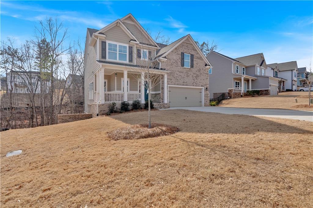 view of front of property featuring a residential view, a front yard, covered porch, driveway, and an attached garage