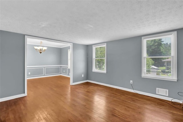 spare room with hardwood / wood-style floors, a notable chandelier, and a textured ceiling