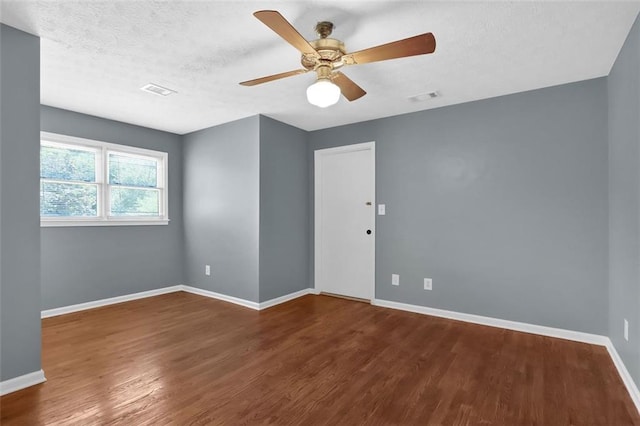 empty room with ceiling fan, dark wood-type flooring, and a textured ceiling