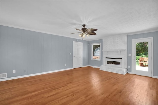 unfurnished living room with a fireplace, crown molding, plenty of natural light, and wood-type flooring