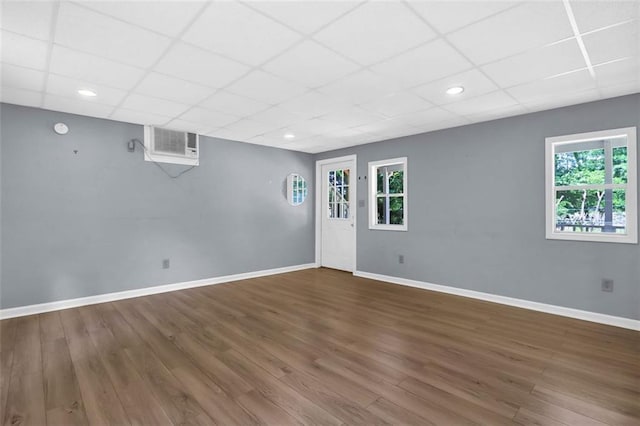 spare room featuring a paneled ceiling, hardwood / wood-style flooring, and a healthy amount of sunlight