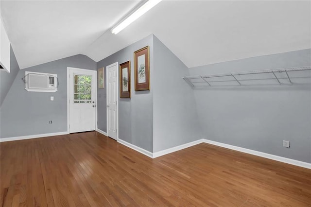 foyer entrance with hardwood / wood-style flooring, a wall unit AC, and lofted ceiling