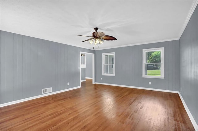 unfurnished room with hardwood / wood-style floors, ceiling fan, ornamental molding, and wood walls