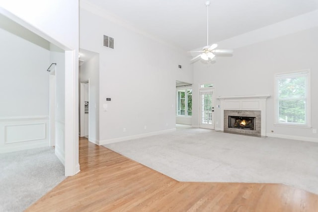 1122 Cayuga Ct, Dacula, GA 30019 - unfurnished living room featuring light carpet, ceiling fan, a premium fireplace, a high ceiling, and light wood finished floors