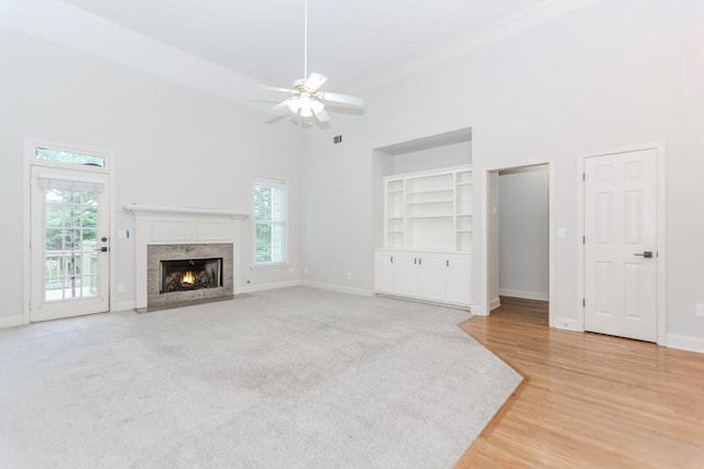 1122 Cayuga Ct, Dacula, GA 30019 - unfurnished living room with a towering ceiling, built in shelves, a ceiling fan, a premium fireplace, and light wood finished floors