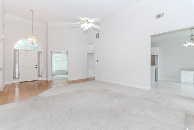 1122 Cayuga Ct, Dacula, GA 30019 - unfurnished living room featuring a chandelier, light carpet, a towering ceiling, ornamental molding, and a ceiling fan