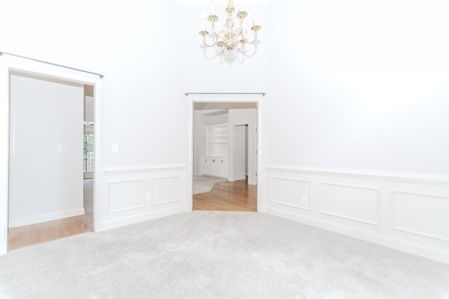 1122 Cayuga Ct, Dacula, GA 30019 - unfurnished room with a chandelier, carpet floors, a decorative wall, wainscoting, and a towering ceiling