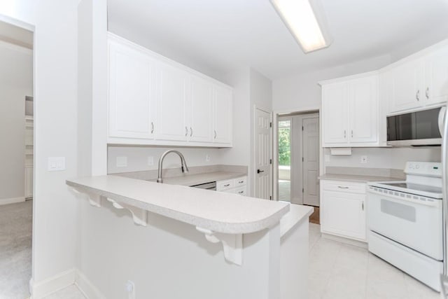 1122 Cayuga Ct, Dacula, GA 30019 - kitchen featuring white electric range oven, stainless steel microwave, light countertops, white cabinetry, and a breakfast bar
