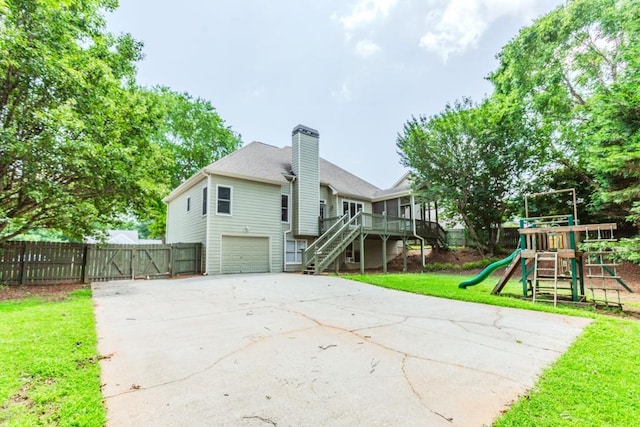 1122 Cayuga Ct, Dacula, GA 30019 - back of house with driveway, a chimney, an attached garage, a playground, and stairs