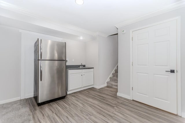 1122 Cayuga Ct, Dacula, GA 30019 - kitchen featuring freestanding refrigerator, light wood-style floors, crown molding, dark stone countertops, and white cabinets