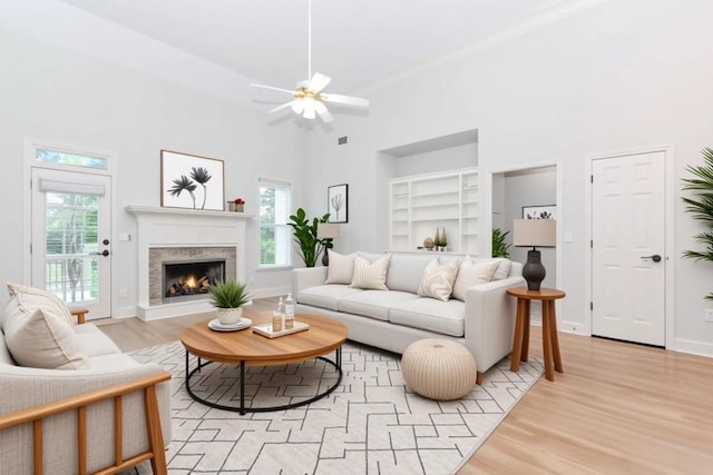 1122 Cayuga Ct, Dacula, GA 30019 - living room featuring high vaulted ceiling, built in shelves, a ceiling fan, light wood-type flooring, and a lit fireplace