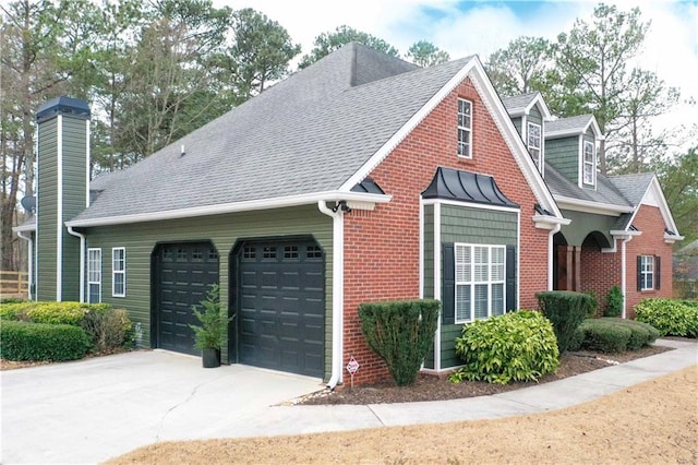 view of side of home with concrete driveway, an attached garage, a shingled roof, brick siding, and a chimney