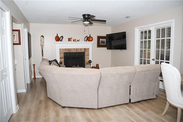 9130 Charlton Pl, Douglasville, GA 30135 - living room featuring light wood-style flooring, ceiling fan, a fireplace, and a textured ceiling