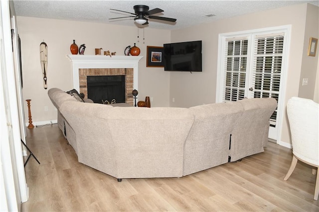 9130 Charlton Pl, Douglasville, GA 30135 - living room featuring a ceiling fan, light wood-style floors, a fireplace, and a textured ceiling