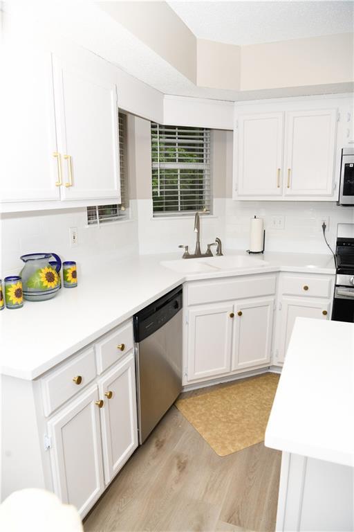 9130 Charlton Pl, Douglasville, GA 30135 - kitchen featuring dishwasher, stove, white cabinetry, and light countertops
