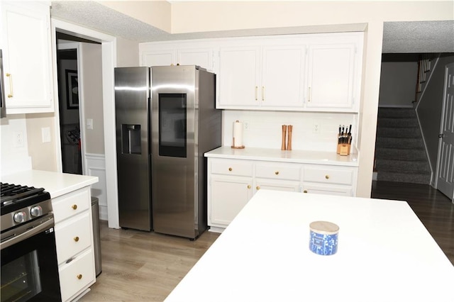 9130 Charlton Pl, Douglasville, GA 30135 - kitchen with appliances with stainless steel finishes, light countertops, white cabinetry, light wood-style flooring, and decorative backsplash