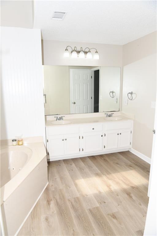 9130 Charlton Pl, Douglasville, GA 30135 - full bathroom featuring wood finished floors, a stall shower, and a textured ceiling