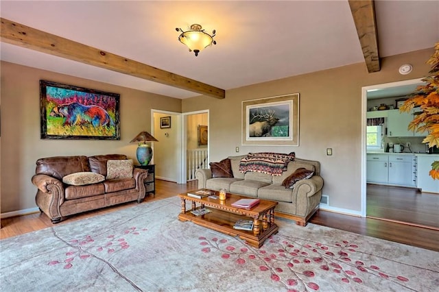 living area featuring beamed ceiling, wood finished floors, and baseboards