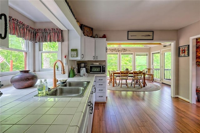 kitchen with tile countertops, stainless steel microwave, a sink, and healthy amount of natural light
