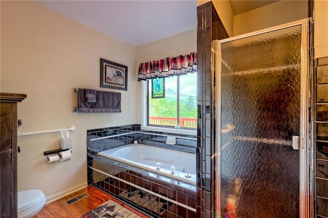 full bath with wood finished floors, baseboards, a garden tub, a shower stall, and toilet