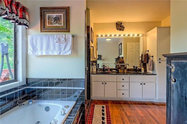 full bath with a whirlpool tub, plenty of natural light, double vanity, and wood finished floors