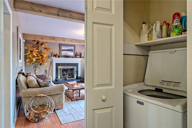 clothes washing area featuring wood finished floors, a tile fireplace, and washer / dryer
