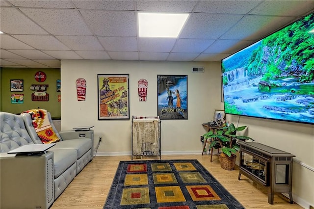 home theater room featuring wood finished floors, a drop ceiling, and baseboards