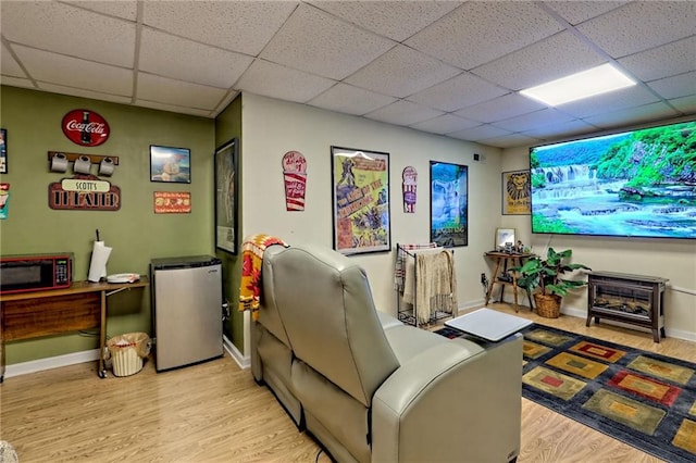 cinema with a drop ceiling, light wood-style flooring, and baseboards