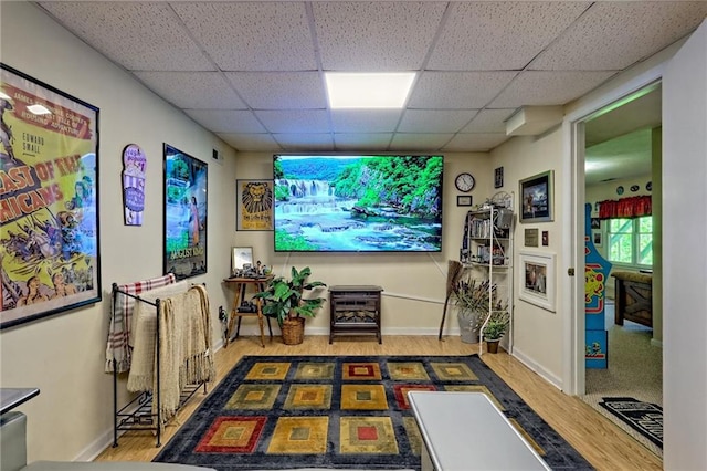 cinema with a paneled ceiling, wood finished floors, and baseboards