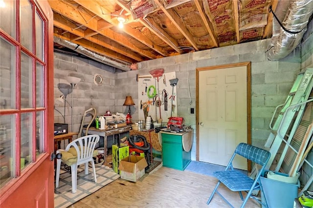unfinished below grade area featuring concrete block wall and a workshop area