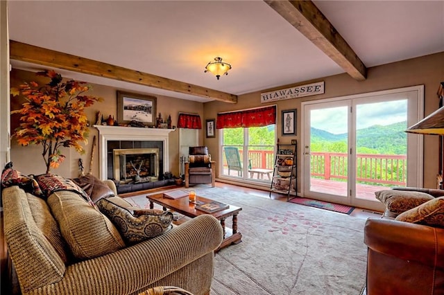 living area featuring beam ceiling, a tiled fireplace, and a mountain view