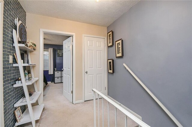 hallway featuring a textured ceiling and light carpet