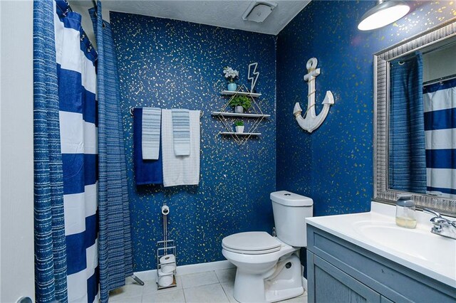 bathroom with toilet, vanity, a textured ceiling, and tile patterned flooring