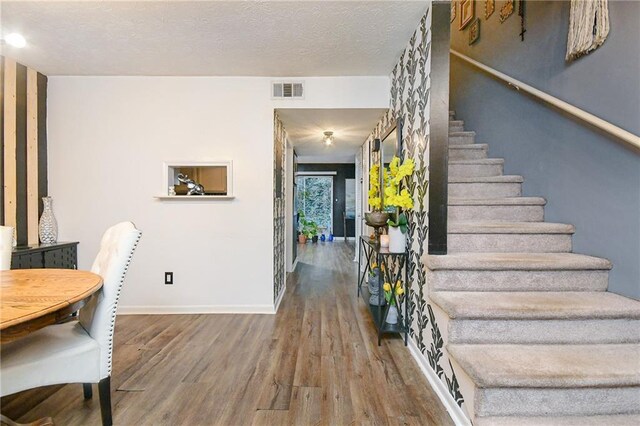 staircase with wood-type flooring and a textured ceiling