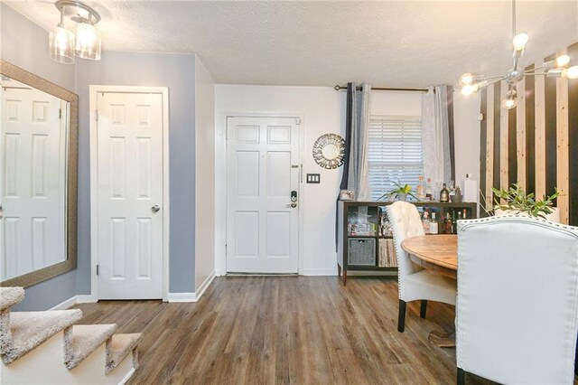 dining space with hardwood / wood-style floors, a textured ceiling, and a notable chandelier