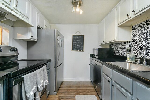 kitchen featuring sink, appliances with stainless steel finishes, hardwood / wood-style floors, and white cabinets