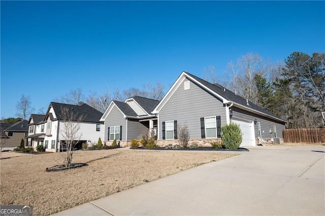 view of front facade featuring an attached garage, concrete driveway, and fence