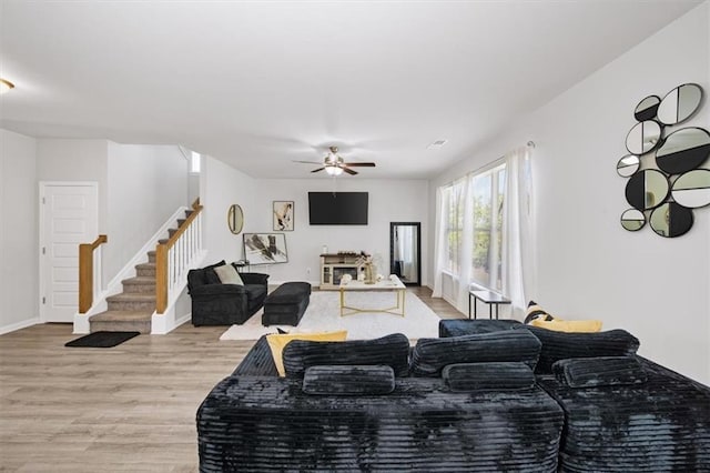 living room with stairway, wood finished floors, a ceiling fan, and baseboards