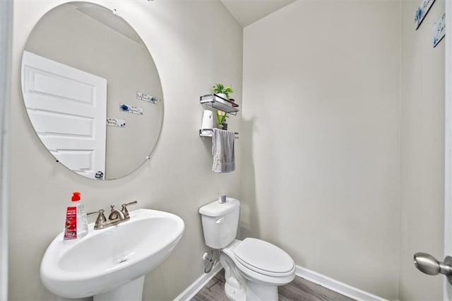 bathroom with a sink, baseboards, wood finished floors, and toilet