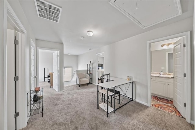 hall featuring attic access, carpet flooring, a sink, and baseboards